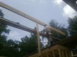 Carpenter setting a ridge beam over a new addition frame — Ice Dam Removal by Roofing Brothers in Sandy Ridge