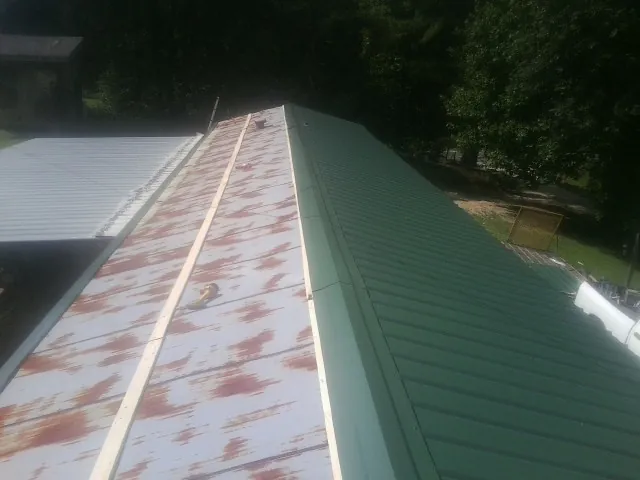 Old rusted panels beside newly installed green metal roofing — Wind Damage Roof Repair by Roofing Brothers in Sandy Ridge