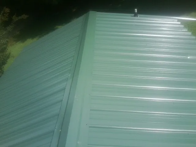 New green metal panels meeting at the ridge of a roof — Flat Roof Repair work by our crew in Sandy Ridge