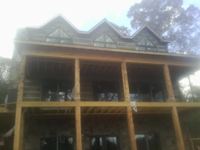 Dormers and porch framing on a large log home under construction — Roof Coating work by our crew in Sandy Ridge