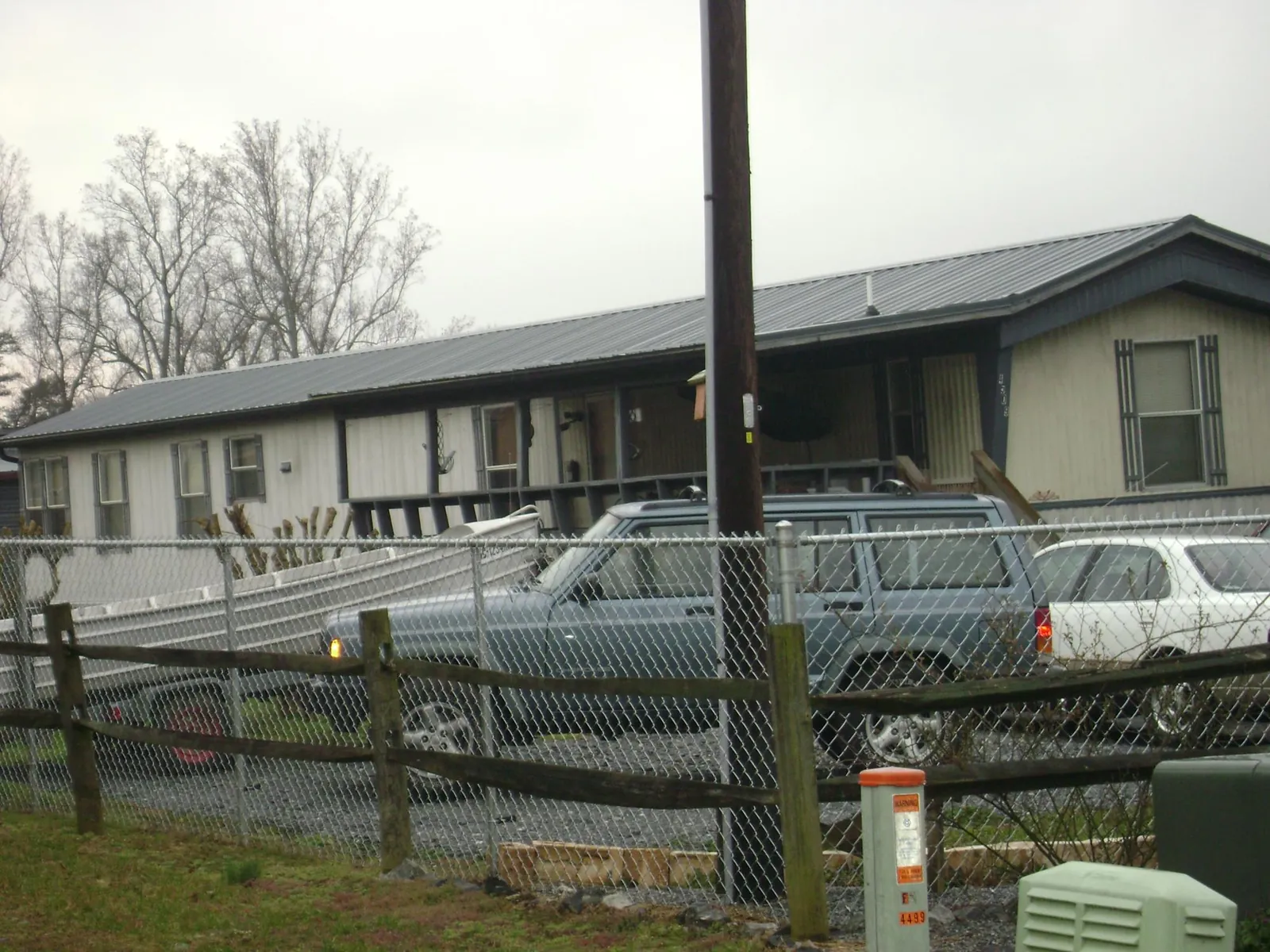 Dark metal roof on a long single story building behind a chain link fence in Sandy Ridge