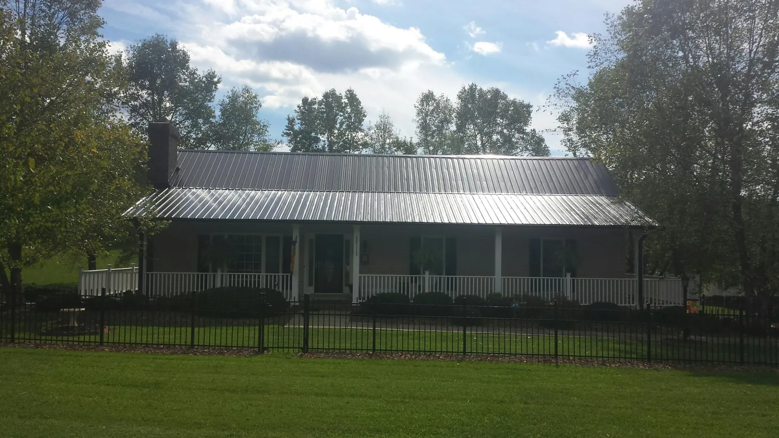 Gray metal roof on a brick ranch with a full width front porch — Gutter Guard Installation work by our crew in Sandy Ridge