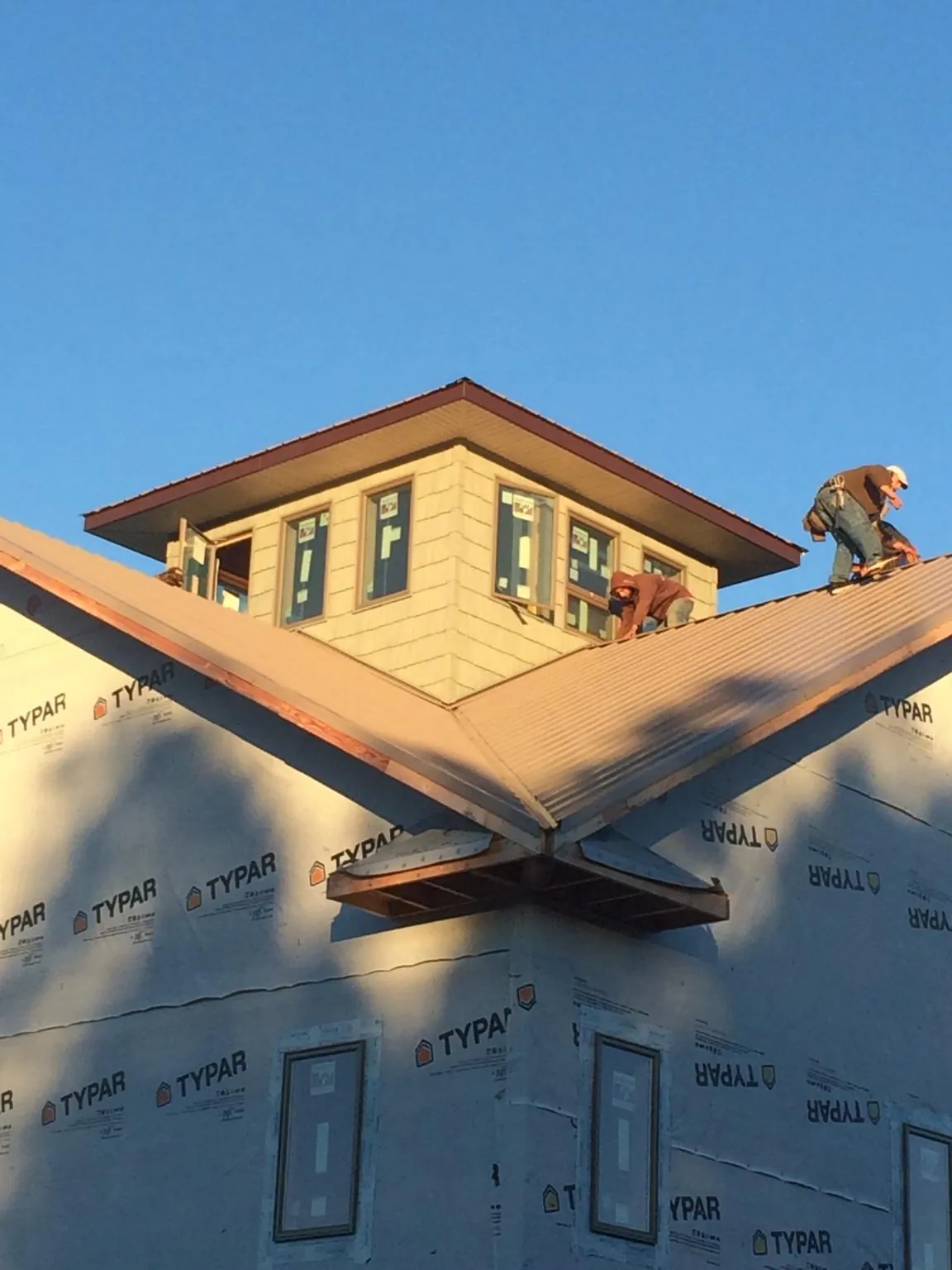 Roofers working around a rooftop cupola on a new metal roof at sunset — Roof Waterproofing in Sandy Ridge by Roofing Brothers